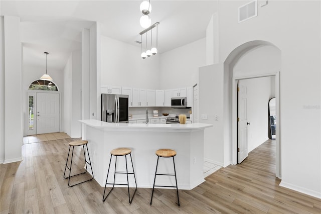 kitchen with visible vents, light countertops, a high ceiling, white cabinets, and stainless steel appliances