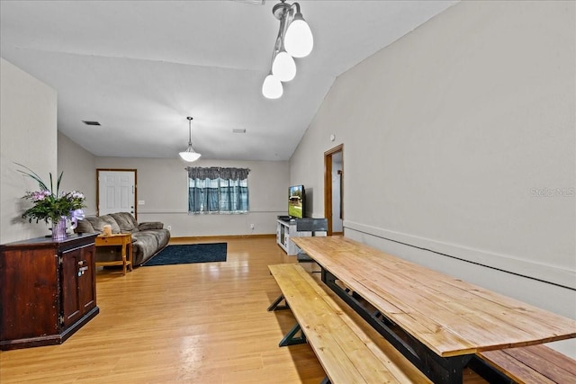 dining area with light hardwood / wood-style flooring and vaulted ceiling