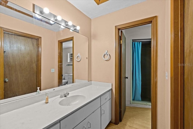 bathroom with a shower with shower curtain, hardwood / wood-style flooring, vanity, and toilet