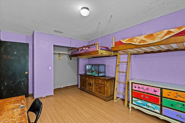 bedroom featuring a textured ceiling and light hardwood / wood-style flooring