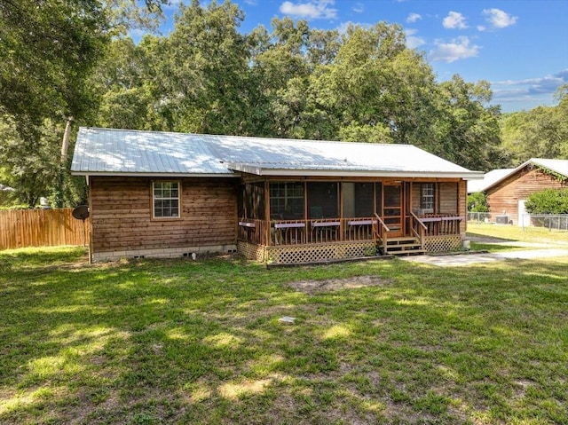 rear view of house with a lawn and a sunroom