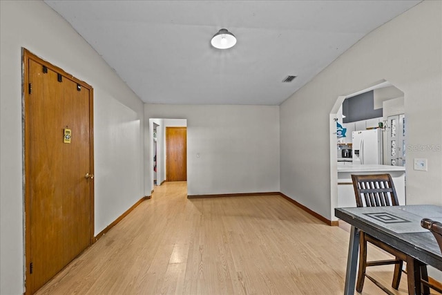 dining space featuring light wood-style floors, visible vents, baseboards, and arched walkways