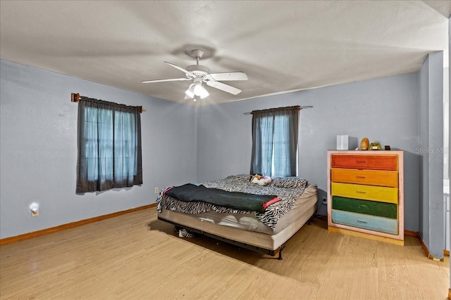 bedroom with ceiling fan, baseboards, and wood finished floors