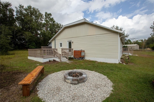 back of house featuring a yard, a deck, and an outdoor fire pit