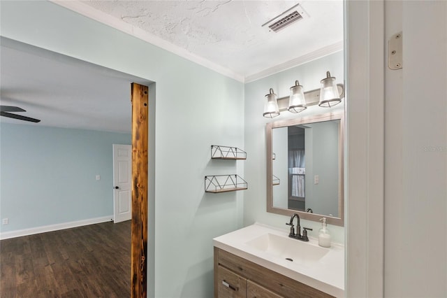 bathroom featuring ornamental molding, hardwood / wood-style flooring, vanity, a textured ceiling, and ceiling fan