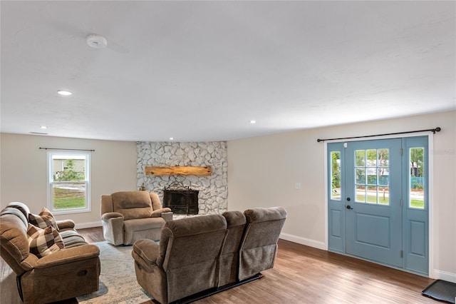 living room featuring light wood-type flooring and a stone fireplace