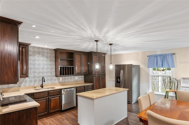 kitchen featuring dark hardwood / wood-style flooring, stainless steel appliances, sink, decorative light fixtures, and a kitchen island