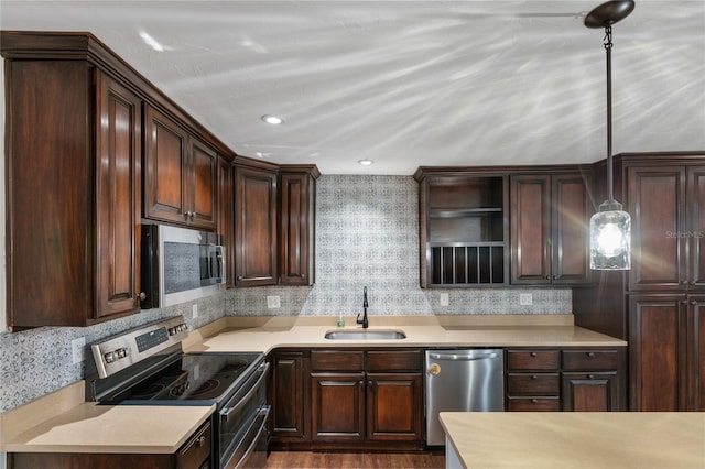 kitchen with appliances with stainless steel finishes, dark brown cabinetry, decorative light fixtures, and sink