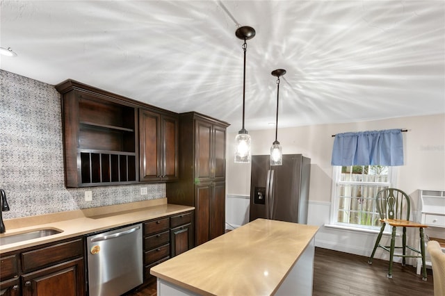 kitchen featuring dark brown cabinetry, sink, stainless steel appliances, dark hardwood / wood-style flooring, and pendant lighting