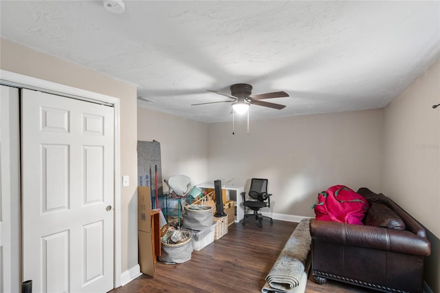 sitting room with ceiling fan and dark wood-type flooring