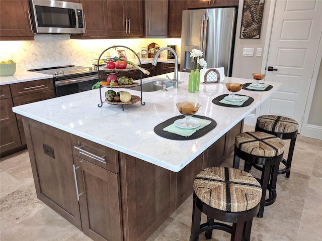6475 SW 74th Dr, Gainesville, FL 32608 - kitchen featuring appliances with stainless steel finishes, a sink, an island with sink, and light stone counters