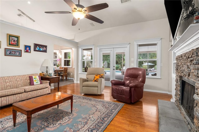 living room with french doors, wood-type flooring, vaulted ceiling, ceiling fan, and a fireplace