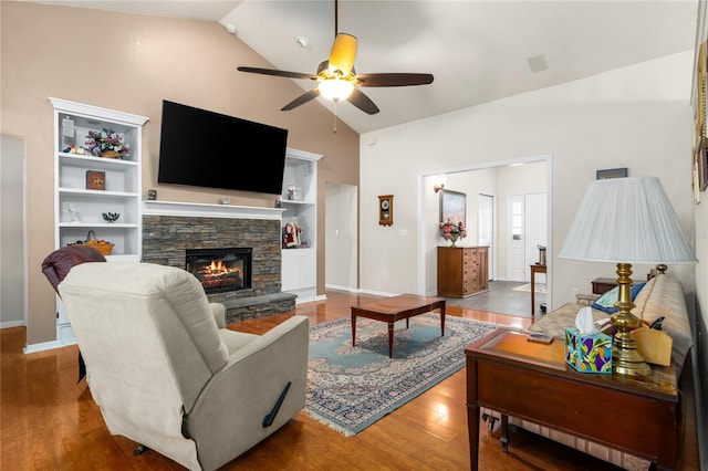 living room featuring a ceiling fan, wood finished floors, a fireplace, high vaulted ceiling, and baseboards