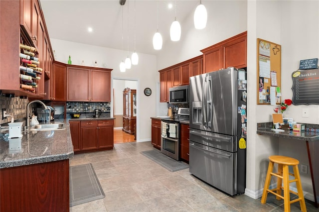 kitchen featuring decorative backsplash, sink, appliances with stainless steel finishes, decorative light fixtures, and dark stone countertops