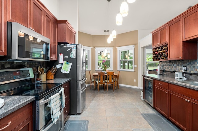 kitchen featuring light tile patterned flooring, stainless steel appliances, decorative light fixtures, decorative backsplash, and beverage cooler