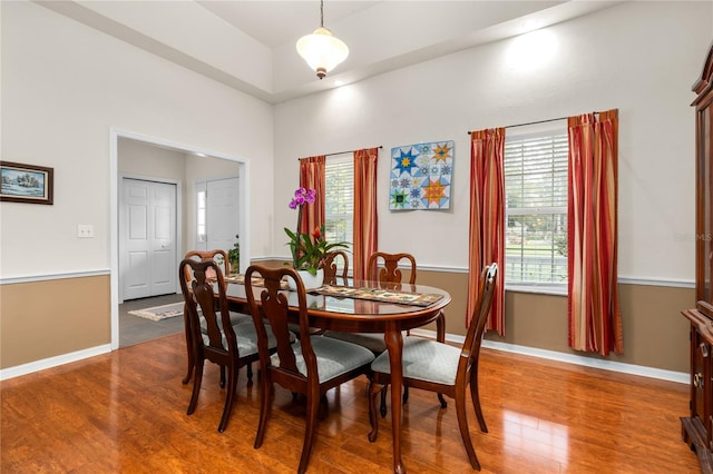 dining area featuring dark wood-style floors, baseboards, and a high ceiling