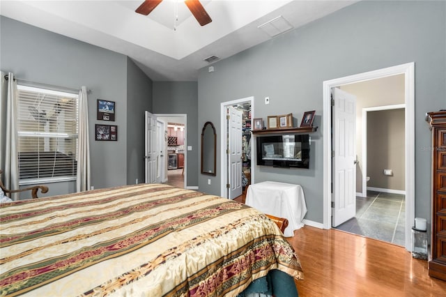 bedroom with wood finished floors, a walk in closet, baseboards, ceiling fan, and a closet