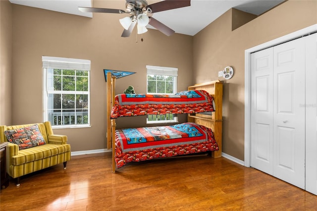 bedroom featuring hardwood / wood-style flooring, ceiling fan, multiple windows, and a closet