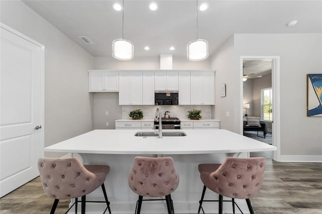 kitchen with white cabinets, a kitchen island with sink, and light wood-type flooring