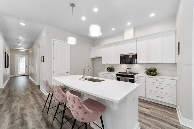 kitchen featuring light hardwood / wood-style floors, stainless steel appliances, a center island with sink, sink, and decorative light fixtures