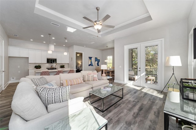 living room with french doors, hardwood / wood-style flooring, ceiling fan, and a raised ceiling