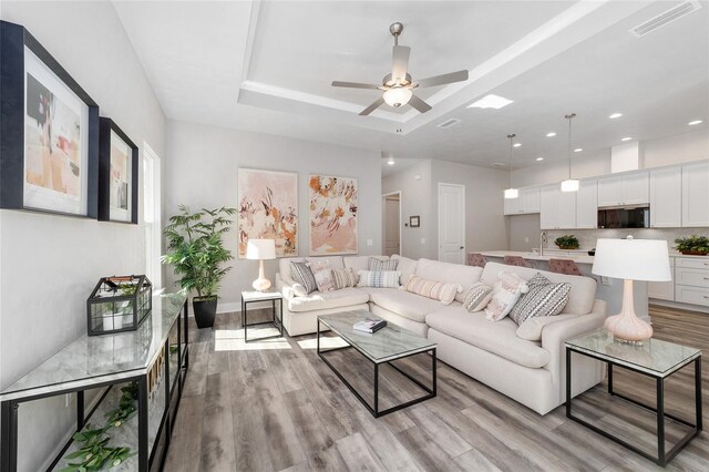 1035 NW 132nd Blvd, Newberry, FL 32669 - living room featuring light wood finished floors, a ceiling fan, a tray ceiling, and recessed lighting