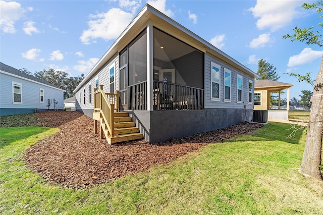 rear view of house featuring central air condition unit, a sunroom, and a yard