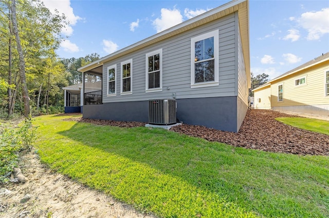 rear view of property featuring a sunroom, a lawn, and central AC