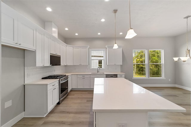 kitchen featuring white cabinetry, stainless steel appliances, sink, and decorative light fixtures