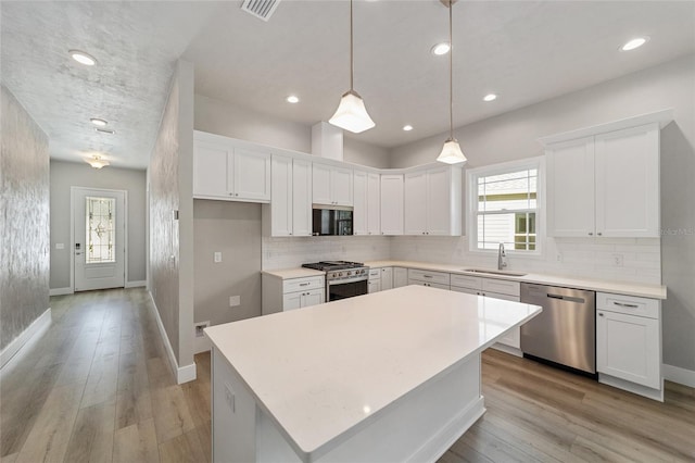 kitchen with white cabinets, light hardwood / wood-style flooring, appliances with stainless steel finishes, and a center island