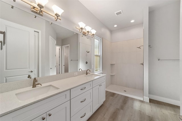 bathroom featuring hardwood / wood-style floors, vanity, and a tile shower