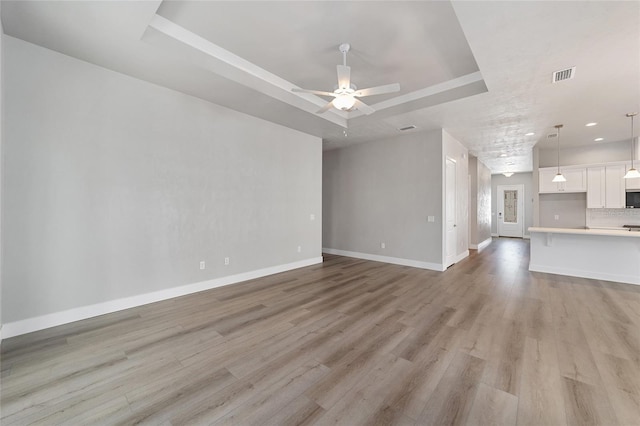 1029 NW 132nd Blvd, Newberry, FL 32669 - unfurnished living room with a raised ceiling, ceiling fan, baseboards, light wood-style floors, and recessed lighting