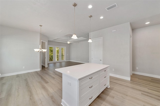 kitchen featuring white cabinetry, ceiling fan with notable chandelier, decorative light fixtures, a kitchen island, and light wood-type flooring