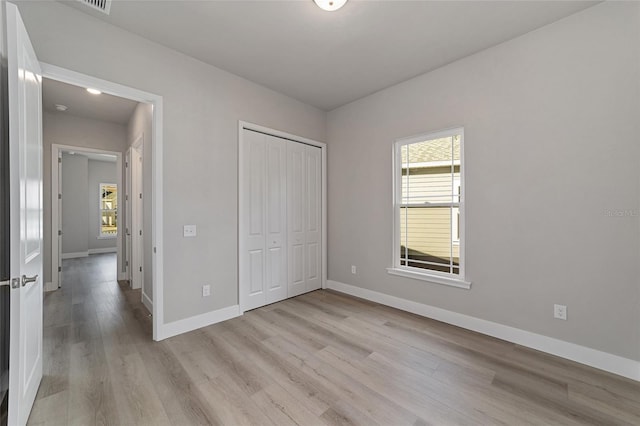 unfurnished bedroom with light wood-type flooring and a closet