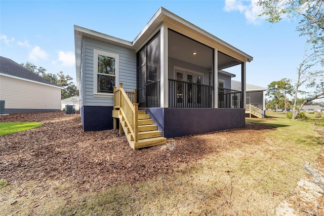 back of property with central AC and a sunroom