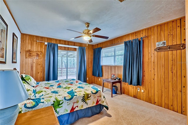 bedroom with multiple windows, carpet, wood walls, and a ceiling fan