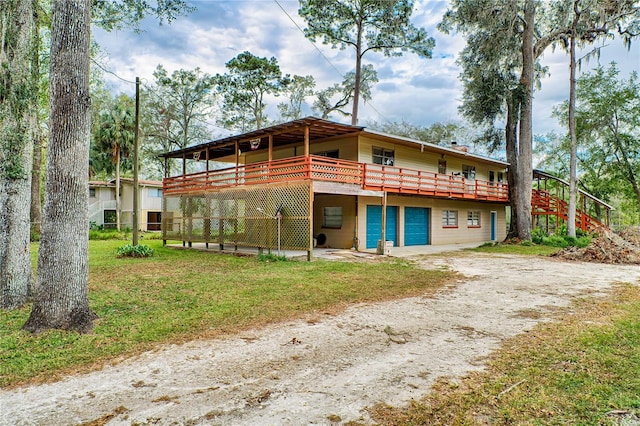 view of front facade featuring a front yard, a garage, driveway, and a wooden deck