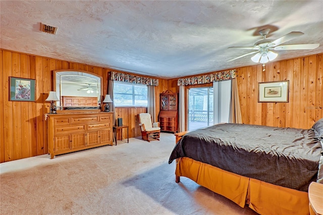 carpeted bedroom featuring visible vents, wood walls, and a textured ceiling