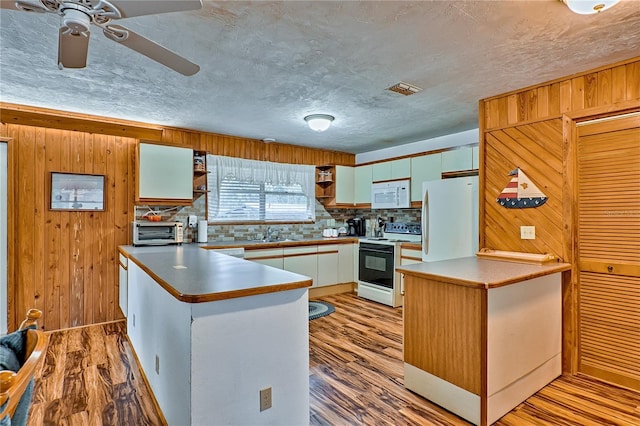 kitchen featuring white appliances, light wood-style flooring, wooden walls, and a peninsula