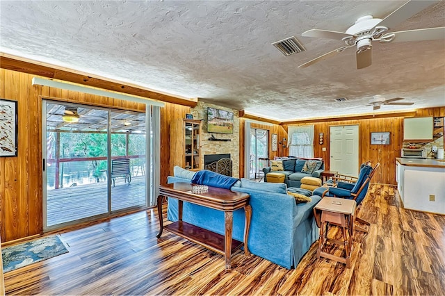 living room featuring wooden walls, visible vents, and a wealth of natural light