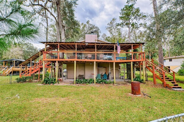 rear view of house featuring fence, stairway, a wooden deck, a lawn, and a patio