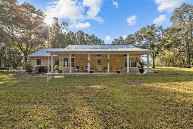 rear view of property with ceiling fan and a yard