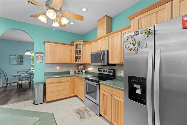 kitchen with ceiling fan, light brown cabinets, tasteful backsplash, light tile patterned floors, and appliances with stainless steel finishes