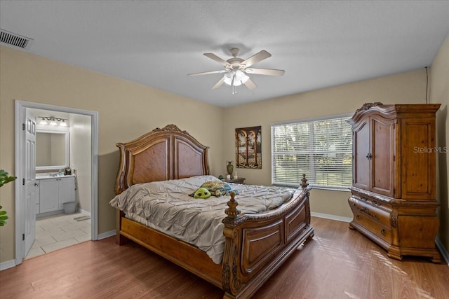 bedroom featuring ensuite bathroom, ceiling fan, and light wood-type flooring