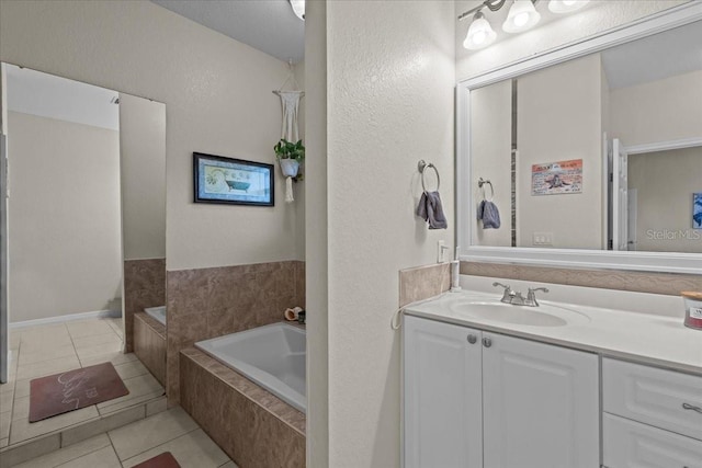 bathroom with tile patterned flooring, vanity, and tiled bath