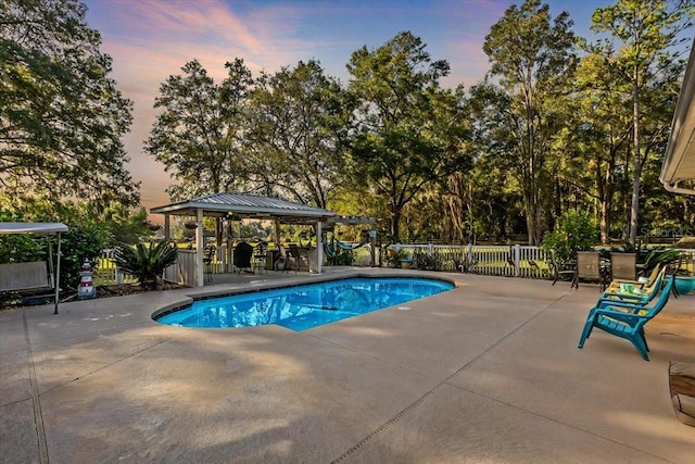 pool at dusk featuring a gazebo and a patio