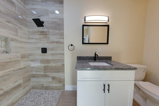 bathroom featuring a tile shower, vanity, toilet, and tile patterned floors