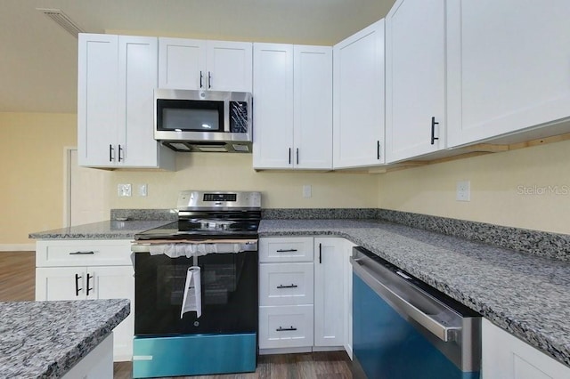 kitchen with light stone counters, white cabinetry, stainless steel appliances, and dark wood-type flooring