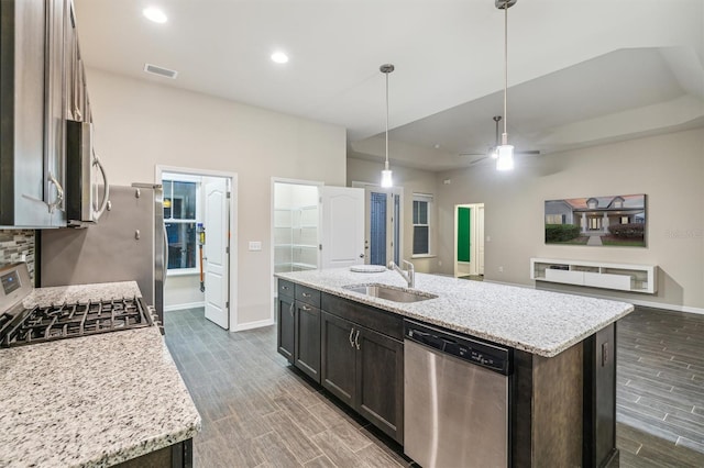 kitchen featuring stainless steel appliances, dark brown cabinetry, pendant lighting, sink, and a kitchen island with sink