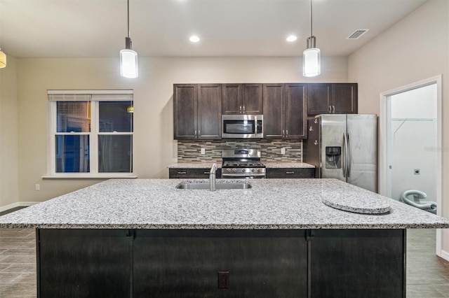 kitchen with a kitchen island with sink, decorative light fixtures, and stainless steel appliances